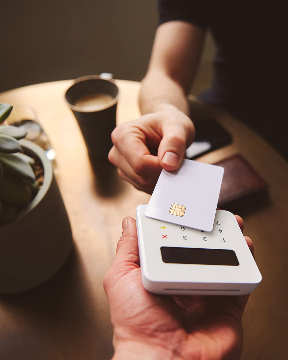 Hand tapping a credit card on a contactless card reader paying f